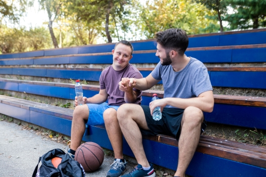 2 jongens langs het veld zittend op bankje geven elkaar een hand